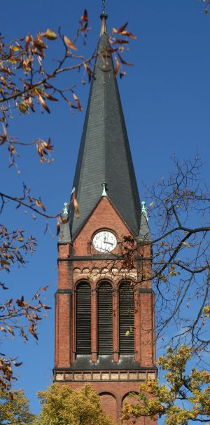 Ein Foto zeigt den oberen Turmschaft der St.Jakobikirche mit der Turmuhr und den SChalluken der Glocken